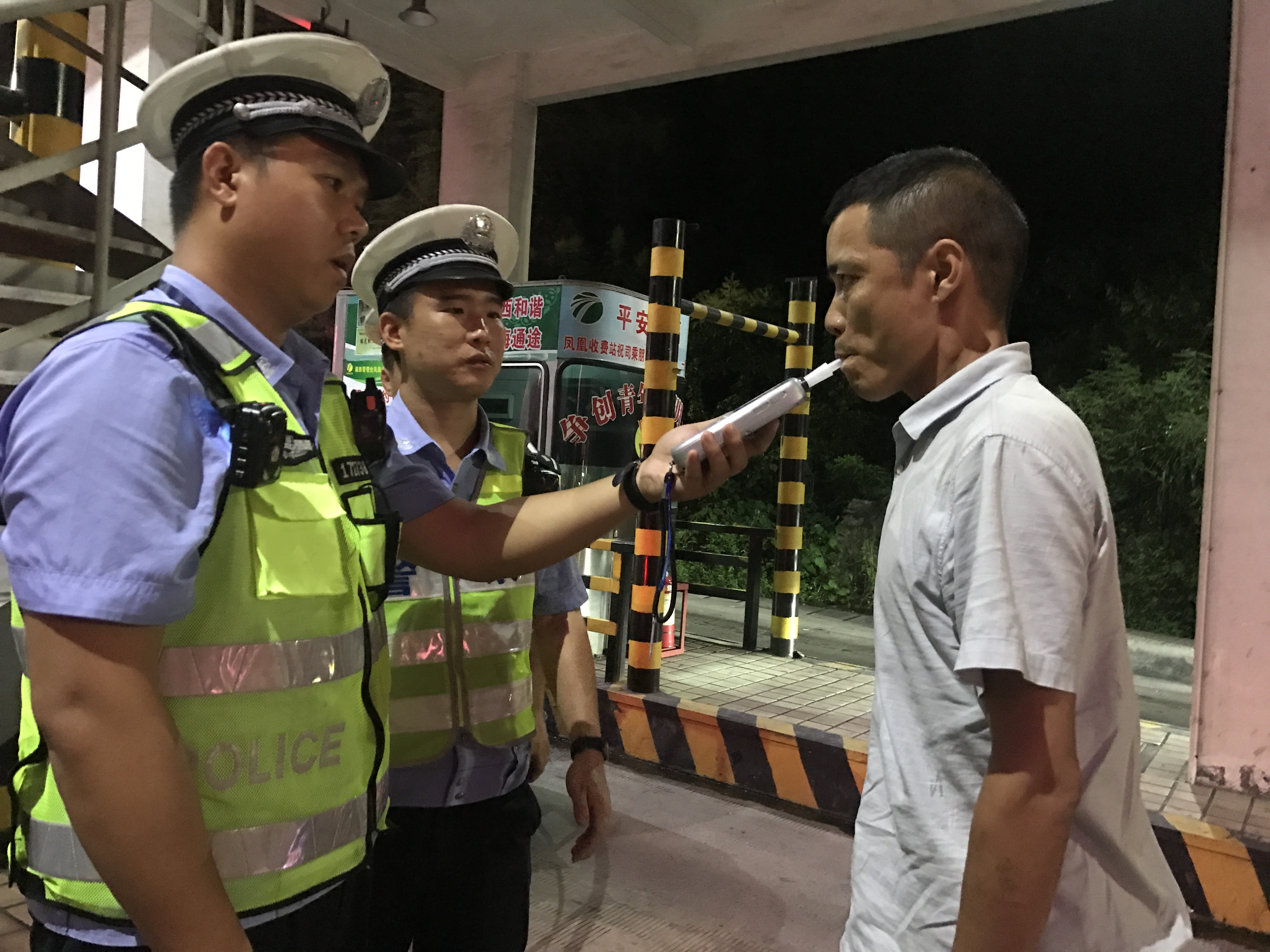 民警梁栋用呼吸式酒精测试仪给疑似酒驾司机做进一步检测.